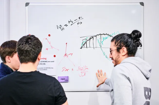 Students evaluating data on whiteboard