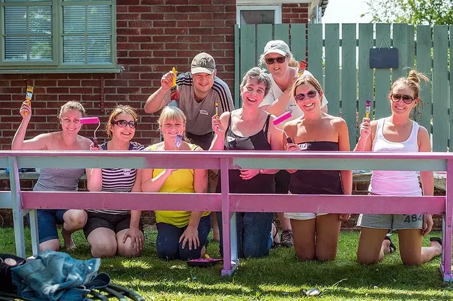 Group of staff painting a fence